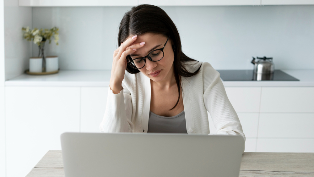 Agente de seguros frustrada frente a su computadora por falta de seguimiento y pérdida de clientes